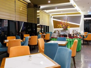 Un ristorante con tavoli e sedie, un bancone con il menu e un'esposizione di fiori.