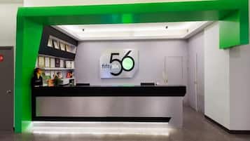 A reception desk with a green accent, a wall-mounted sign reading '56', and a counter with various items.