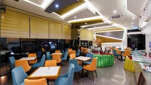 Interior moderno de restaurante com várias mesas e cadeiras, um espaço de buffet e um balcão.