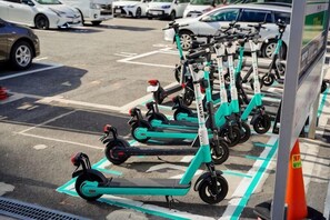 Un parking où plusieurs trottinettes électriques sont alignées.