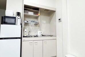 Une petite cuisine équipée d’un four à micro-ondes, d’une machine à café et de placards de rangement.