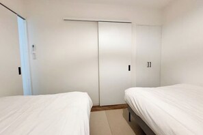 Ein Schlafzimmer mit zwei Betten, einem Kleiderschrank und einer Tür.