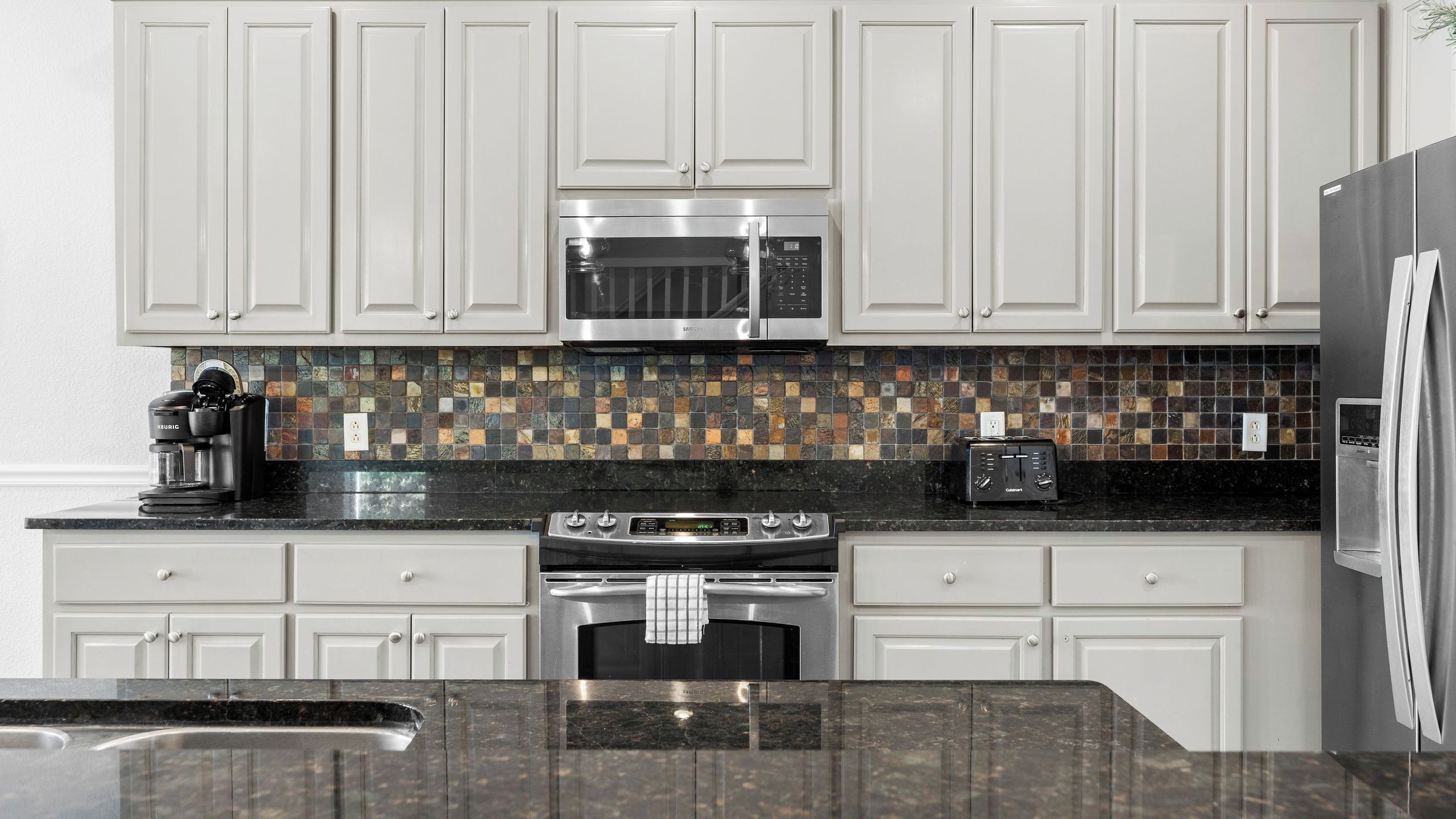 A kitchen with white cabinets, a microwave, a toaster, and a coffee maker.