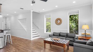 A spacious living room with a grey sofa, a wooden coffee table, and a staircase leading to another level.