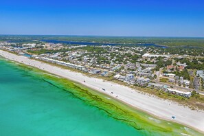 An aerial view of a coastal town with a long sandy beach, clear turquoise waters, and a mix of residential and commercial buildings. - Southfields Retreat 4BR Getaway Near Laguna Beach, Carillon & Pier Park (Panama City Beach)