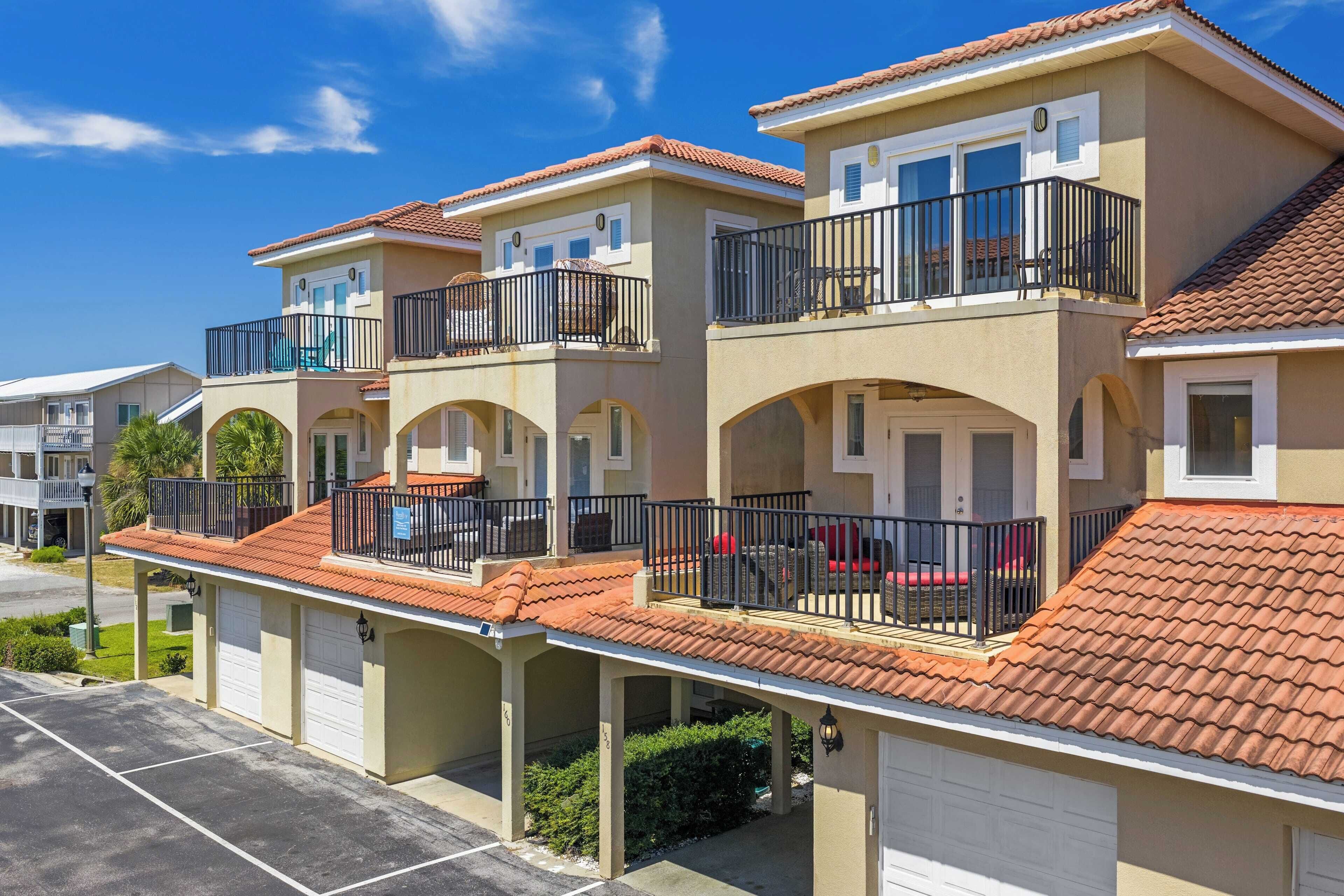 Una hilera de casas urbanas con balcones, puertas de garaje y cielo despejado.