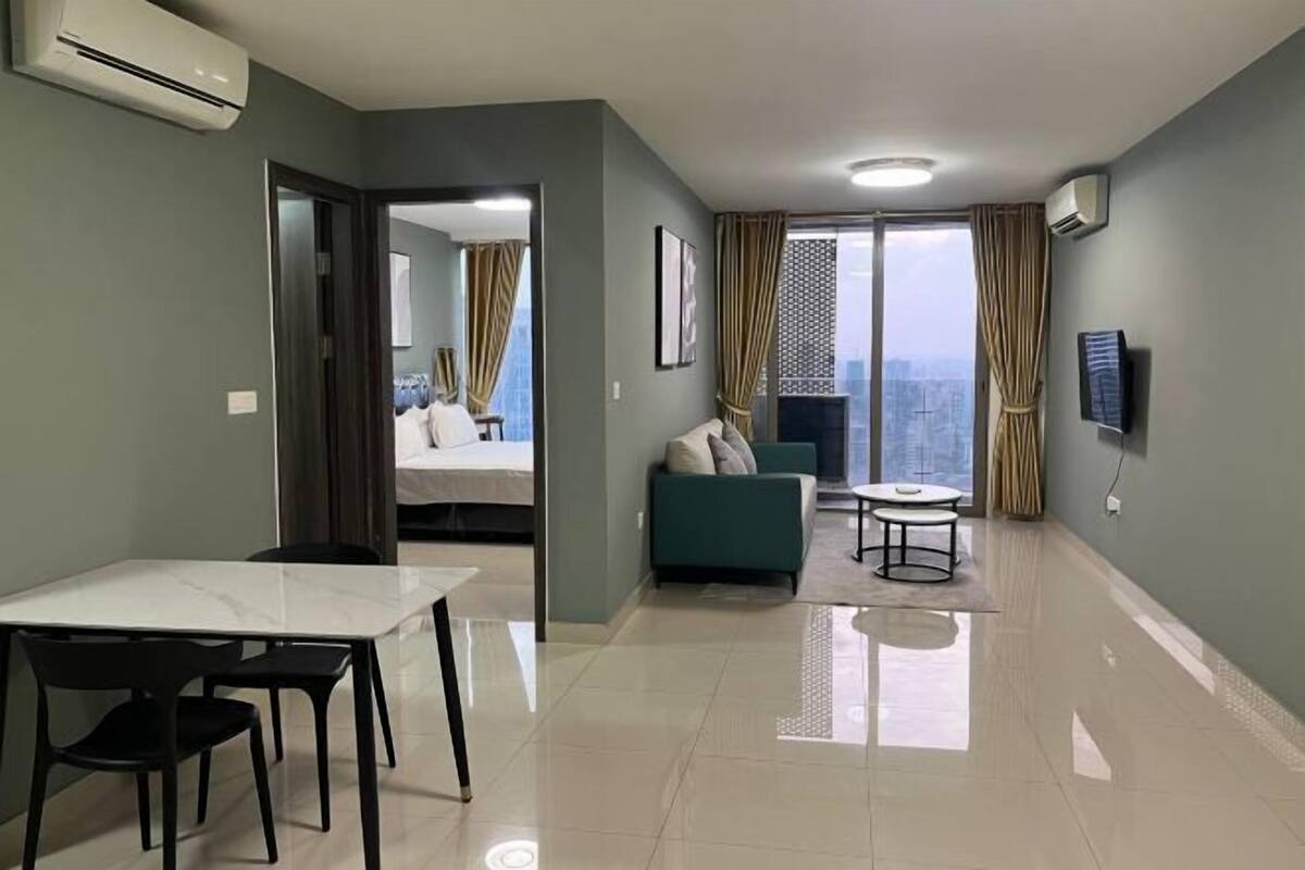 Ein modernes Wohnzimmer mit Essbereich, einer Couch, einem Fernseher und einem Balkon mit Stadtblick.