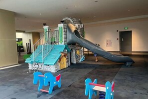 A children's play area with a slide, climbing structures, and toy horses. - The Peak Service Apt By David (Phnom Penh)