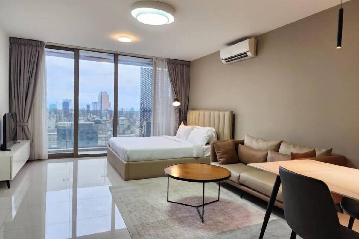 Ein modernes Hotelzimmer mit einem großen Bett, einer Couch, einem Esstisch und Blick auf die Stadt.