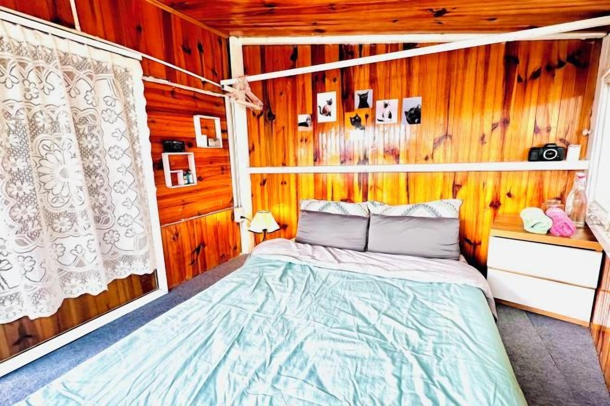 A four-poster bed with a wooden headboard, a bedside table, and a nightstand.