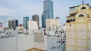 A rooftop with a view of a city skyline, including modern high-rise buildings and a decorative white fence. - Ben Thanh Luxury Suite Hotel (Ho Chi Minh City)