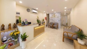 A hotel reception area with a reception desk, seating, and a staircase leading to the upper floor. - Ben Thanh Luxury Suite Hotel (Ho Chi Minh City)
