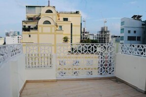 A rooftop terrace with a white metal fence, a view of a yellow building, and a clear sky. - Ben Thanh Luxury Suite Hotel (Ho Chi Minh City)