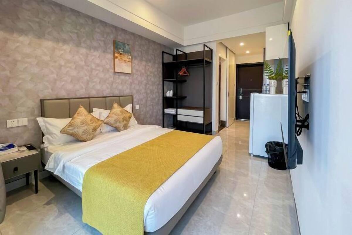 Une chambre d’hôtel moderne équipée d’un lit, d’une table de chevet et d’une armoire intégrée.