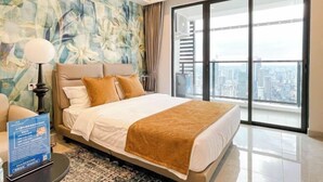 Habitació d'hotel moderna amb un llit gran, vista a la ciutat i una paret decorativa.