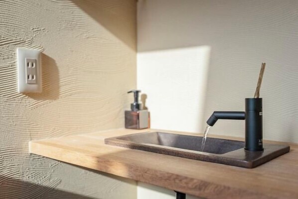 A bathroom with a wooden countertop, a black faucet, and a visible electrical outlet.