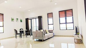 A spacious living room with a sofa, a dining table with chairs, and large windows with blinds. - Double Storey Pool at Trio Setia Klang by HCK (Port Klang)