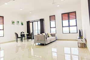A spacious living room with a sofa, a dining table with chairs, and large windows with blinds. - Double Storey Pool at Trio Setia Klang by HCK (Port Klang)