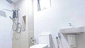 A bathroom with a toilet, a shower, and a window.