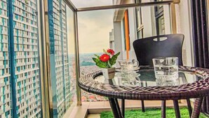A balcony with a glass table, a chair, a potted plant, and a view of a cityscape. - Double Storey Pool at Trio Setia Klang by HCK (Port Klang)