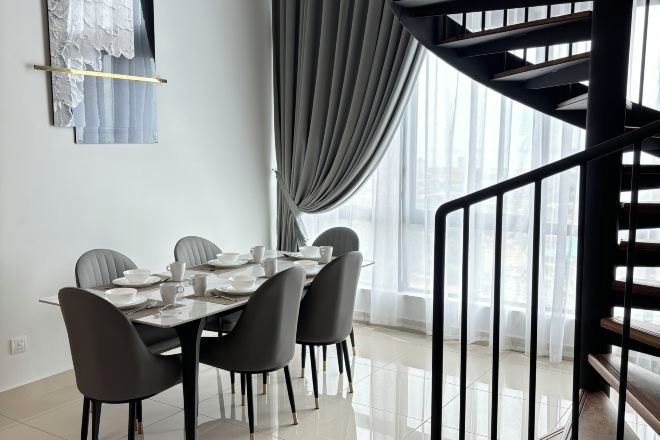 Un comedor con una mesa preparada para cuatro, una escalera y vistas al exterior.