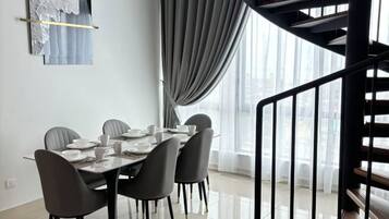 Un comedor con una mesa preparada para cuatro, una escalera y vistas al exterior.