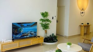 Un salon moderne avec un téléviseur à écran plat, des meubles en bois, une plante en pot et une table basse ronde.