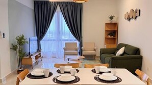 Un salon moderne avec une table à manger pour quatre personnes, un canapé, un fauteuil et une bibliothèque.