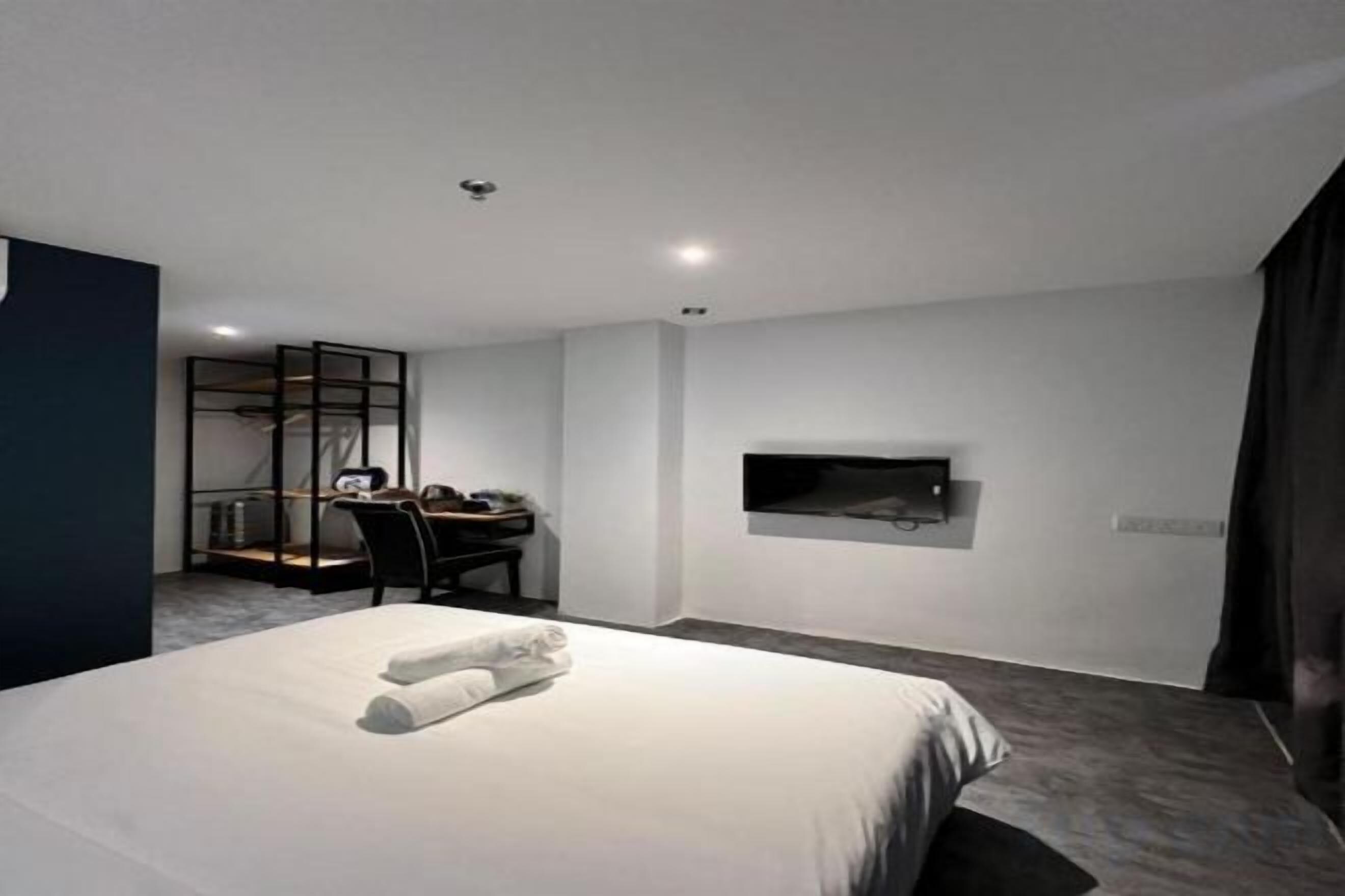 A modern hotel room with a large bed, a desk, and a TV mounted on the wall.