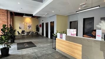 A reception area with a wooden counter, a seating area with chairs, and a staircase leading to an upper level.