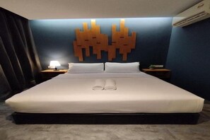Een hotelkamer met een groot bed, een wandlamp en een nachtkastje met lamp.