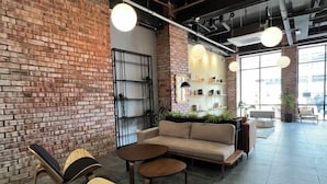A modern lounge area with a brick wall, a sofa, two chairs, and a small table. - Kingston Hotel 7 @ Johor Bharu (Johor Bahru)