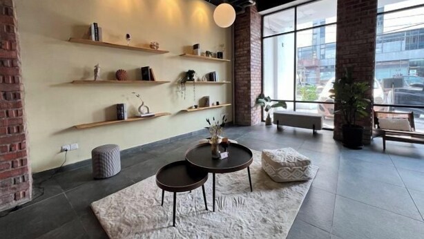 A modern interior with exposed brick walls, wooden shelves, a round table, and a bench. - Kingston Hotel 7 @ Johor Bharu (Johor Bahru)