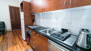 Una cocina con gabinetes de madera, un lavamanos de acero inoxidable y un hervidor.