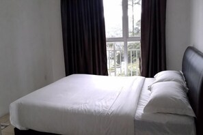 Una cama con ropa de cama blanca, un cabecero oscuro y una ventana con cortinas.