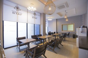 Une salle de conférence moderne, située dans un hôtel, avec des tables et des chaises, un grand écran et un éclairage décoratif.