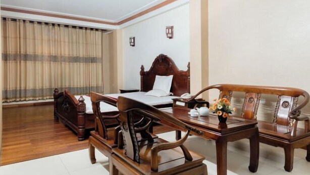 A hotel room with a wooden bed, a wooden sofa, a wooden table, and a curtain. - Vuong Dinh Hotel (Vinh City)
