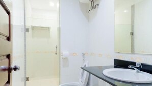 A bathroom with a glass shower enclosure, a white toilet, a sink with a black countertop, and a mirror above the sink. - Vuong Dinh Hotel (Vinh City)