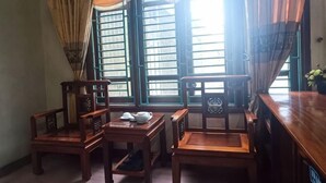 A room with wooden furniture, including chairs and a table, near a window with curtains. - Vuong Dinh Hotel (Vinh City)
