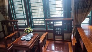 A traditional wooden room with a table set for tea, a chair, and a window with green blinds. - Vuong Dinh Hotel (Vinh City)