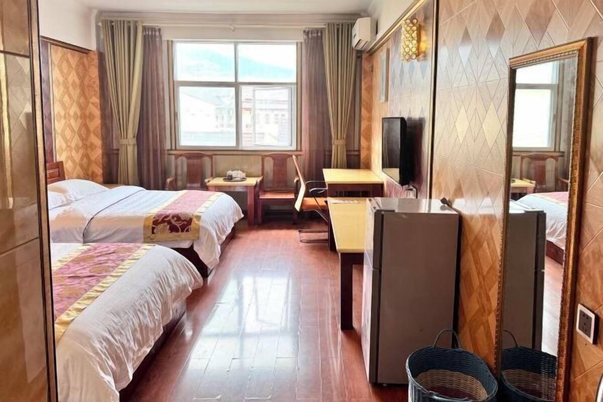 A hotel room with two beds, a desk, a chair, a television, and a large mirror.