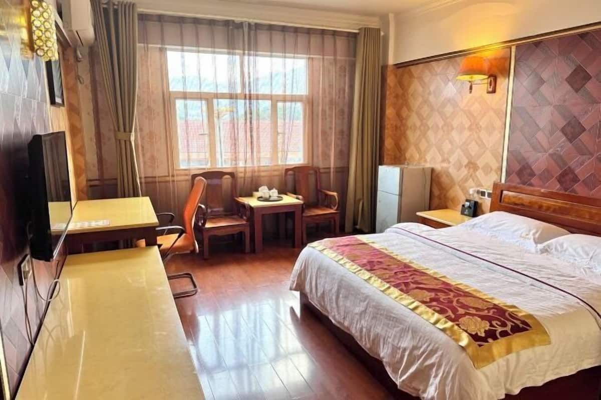 A hotel room with a bed, a desk, a chair, and a television.