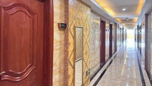Pasillo de hotel con paredes de mármol, puertas de madera y un cartel que indica la habitación 410.