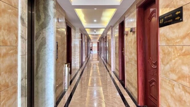 Un largo pasillo bien iluminado, con paredes y puertas de mármol, que conduce a varias habitaciones.