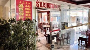 Un restaurante con fachada de vidrio, mesas en el interior y un letrero rojo.