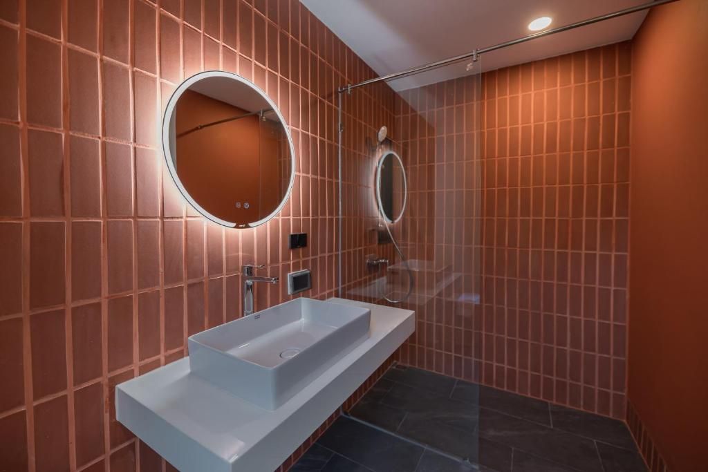 A modern bathroom with a rectangular sink, two wall-mounted mirrors, and a shower area.