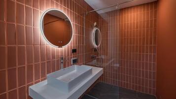A modern bathroom with a rectangular sink, two wall-mounted mirrors, and a shower area.