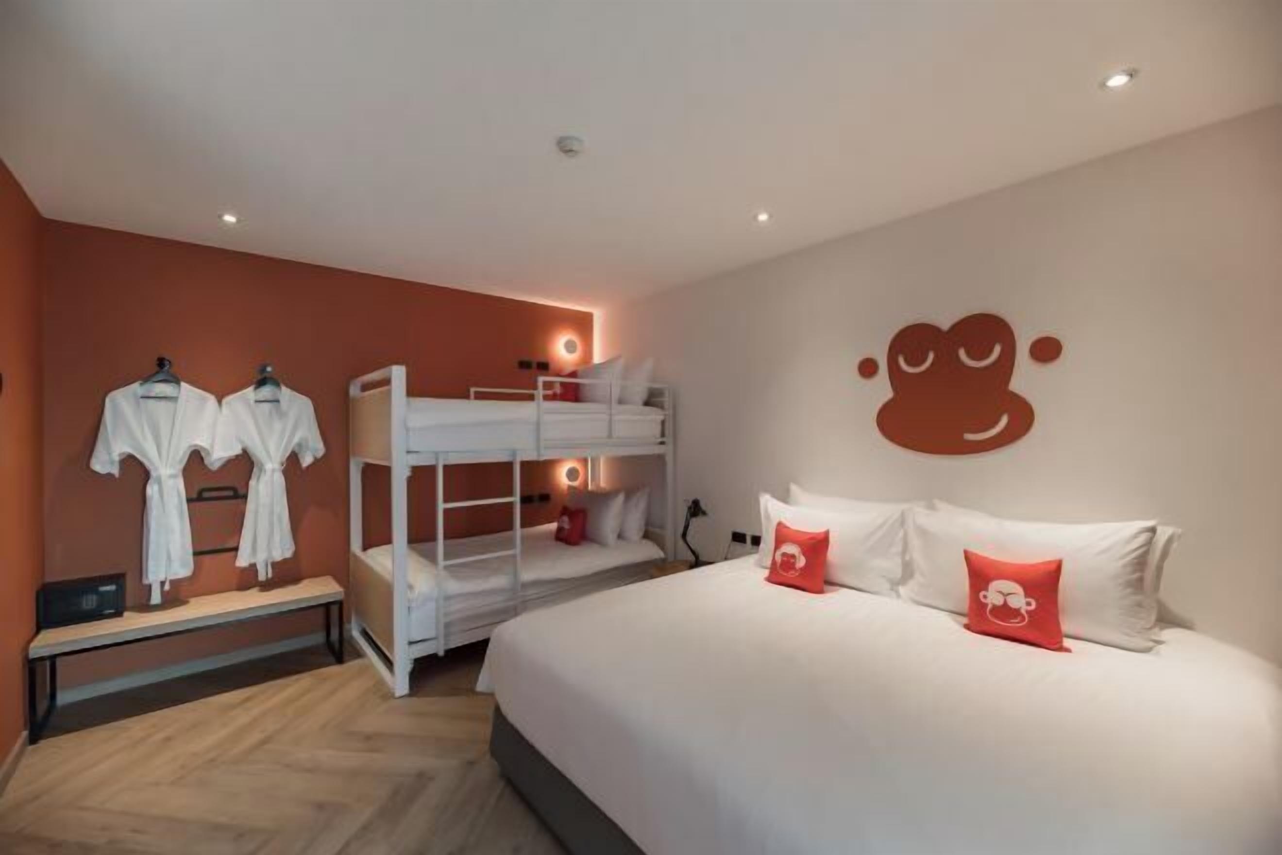 Ein Hotelzimmer mit einem Etagenbett, einem großen Bett mit Kissen und einer Wand mit einer Zeichentrickfigur.