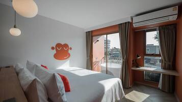 Habitación de hotel con cama, escritorio, aire acondicionado y vistas al exterior.