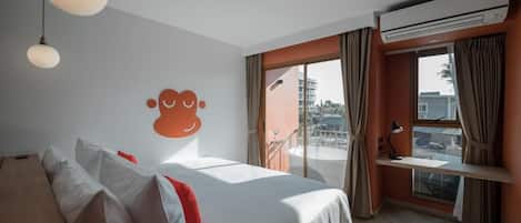 Habitación de hotel con cama, escritorio, aire acondicionado y vistas al exterior.